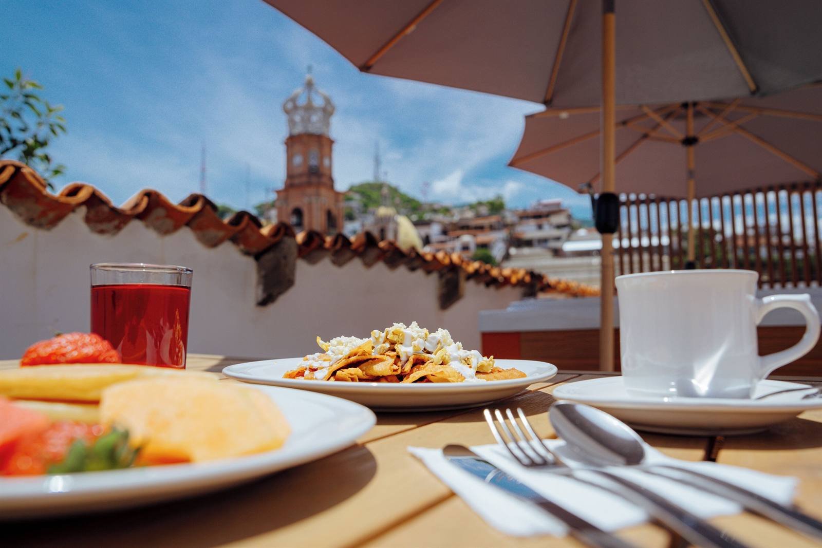 Hotel Casa Kavia: breakfast on the rooftop terrace under an umbrella, with the church tower in the background